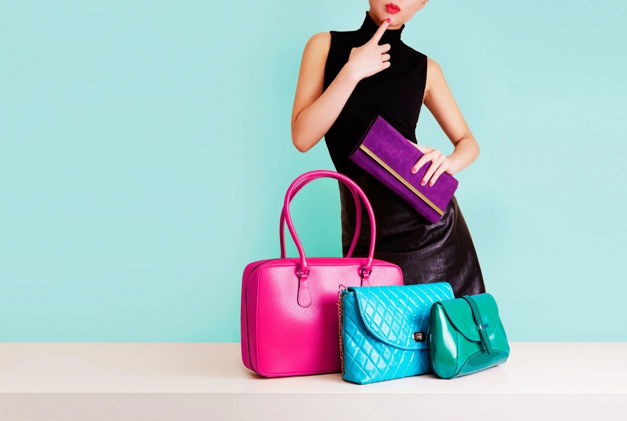 A woman holding onto some purses in front of her
